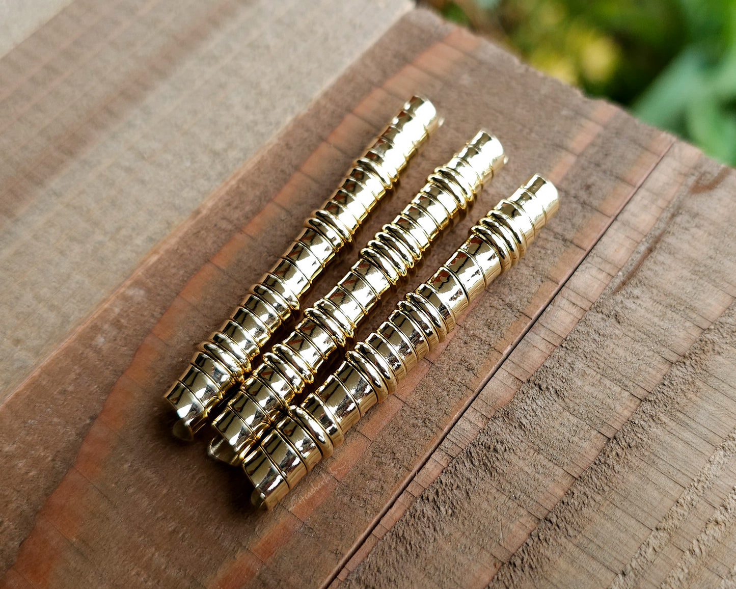 A set of brass hair coils on a wood surface.