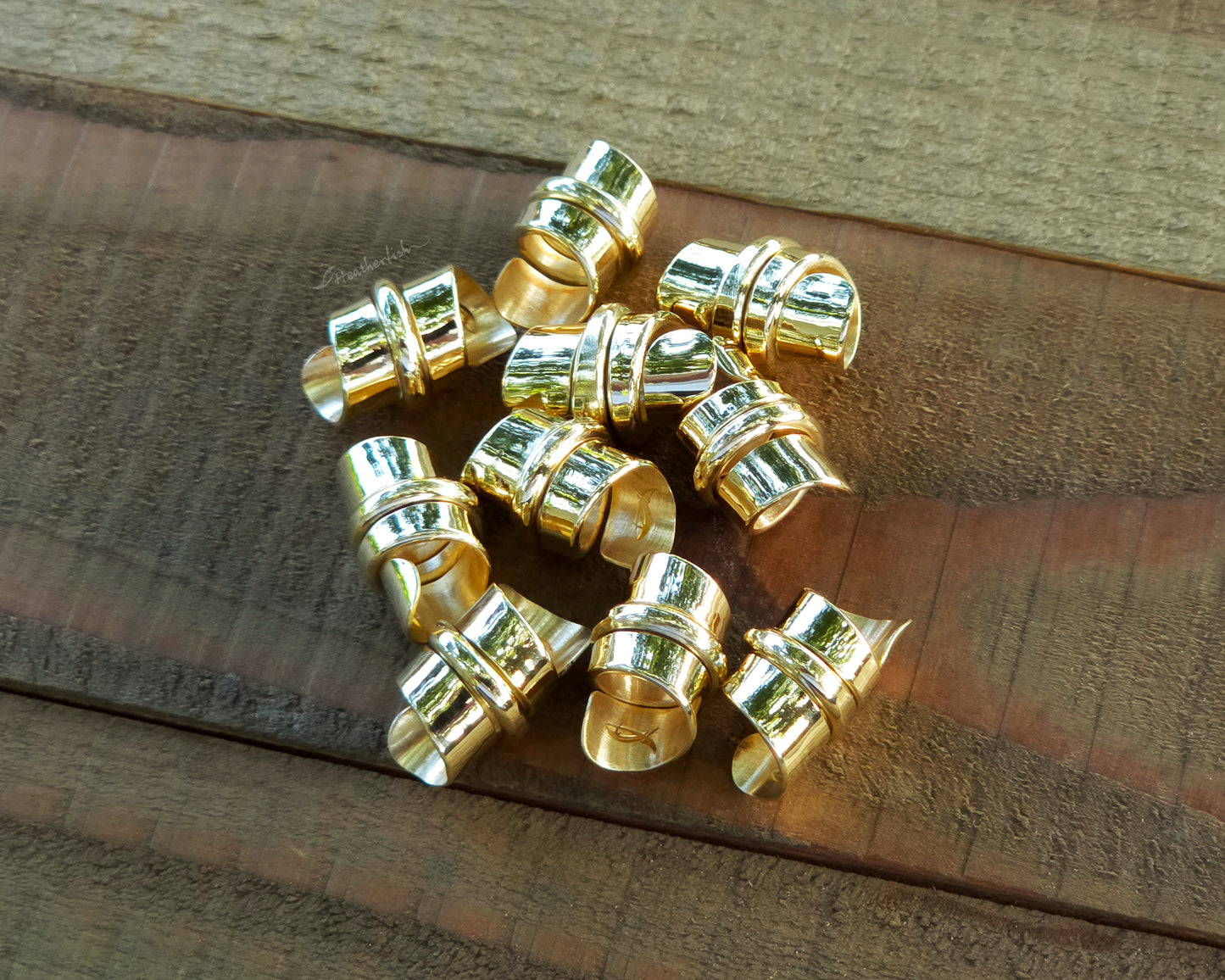 Red brass hair beads on a wood background.
