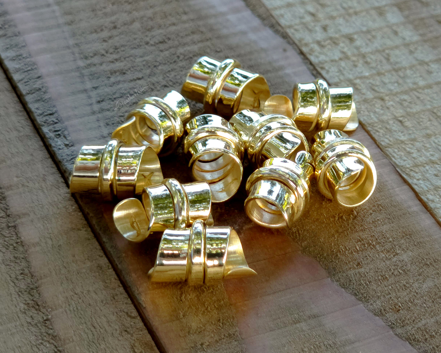 Red brass hair beads on a wood background.