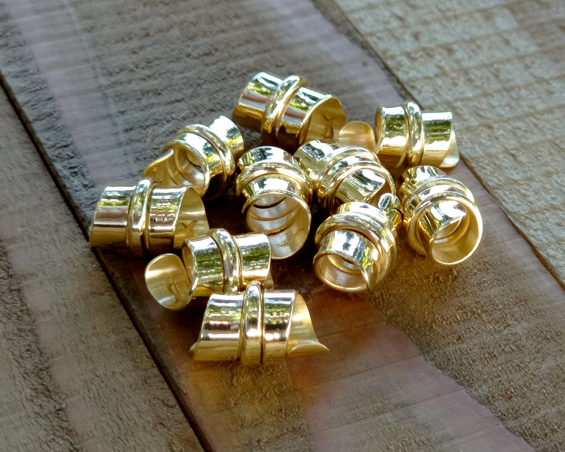 Red brass hair beads on a wood background.