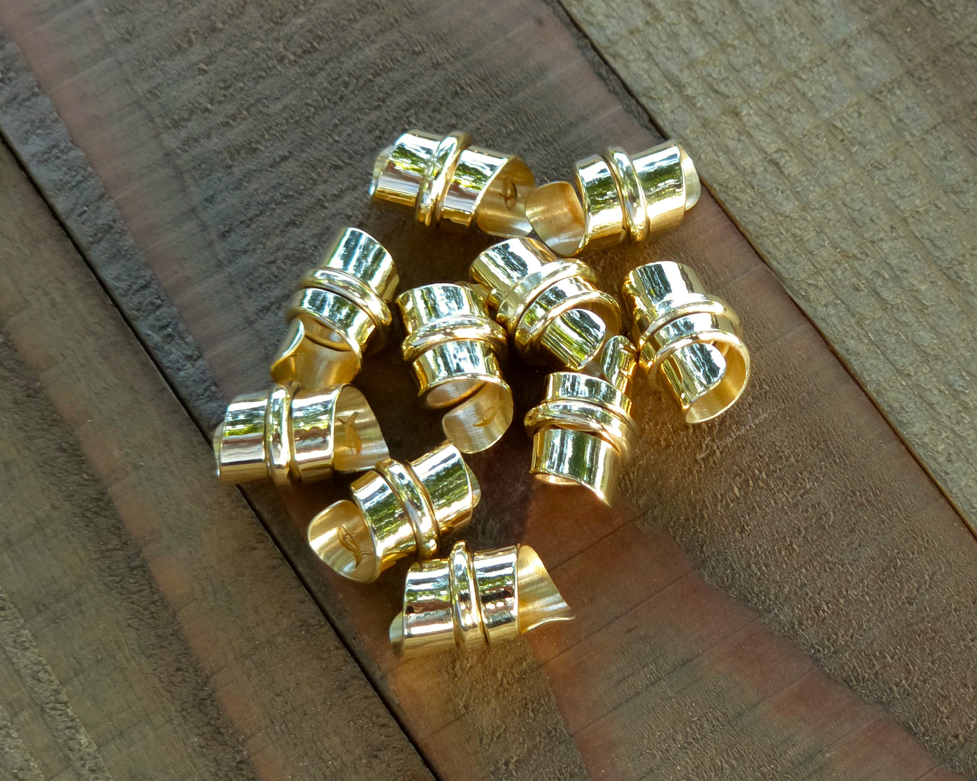 Red brass hair beads on a wood background.