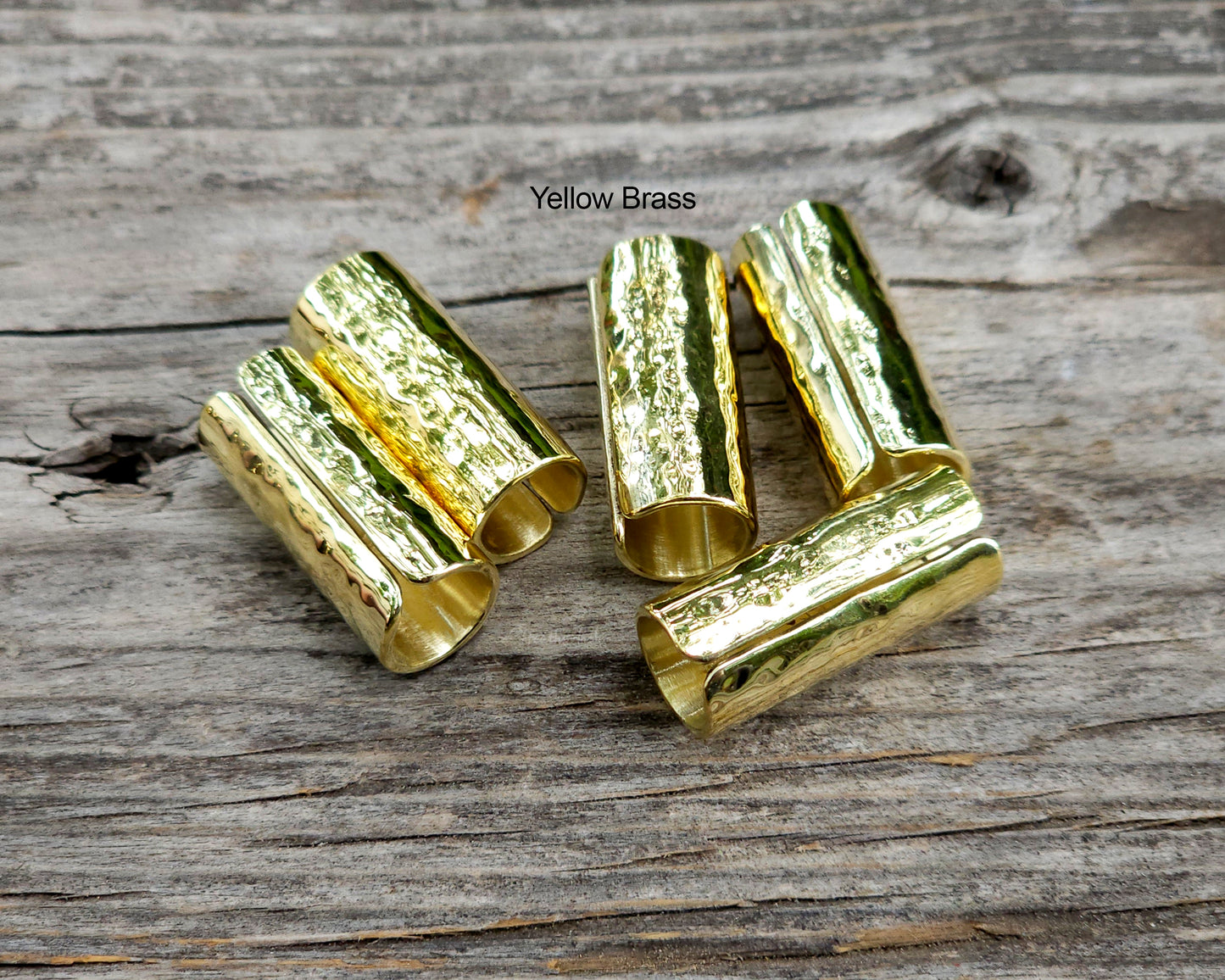 Yellow brass hair cuffs on a wood surface.