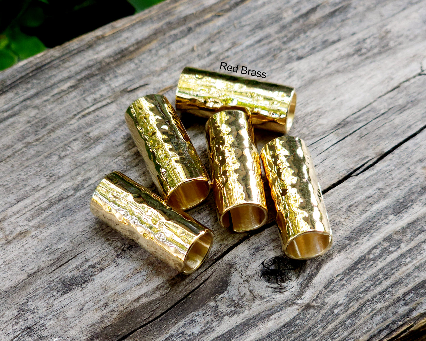 Red brass hair cuffs on a wood surface.