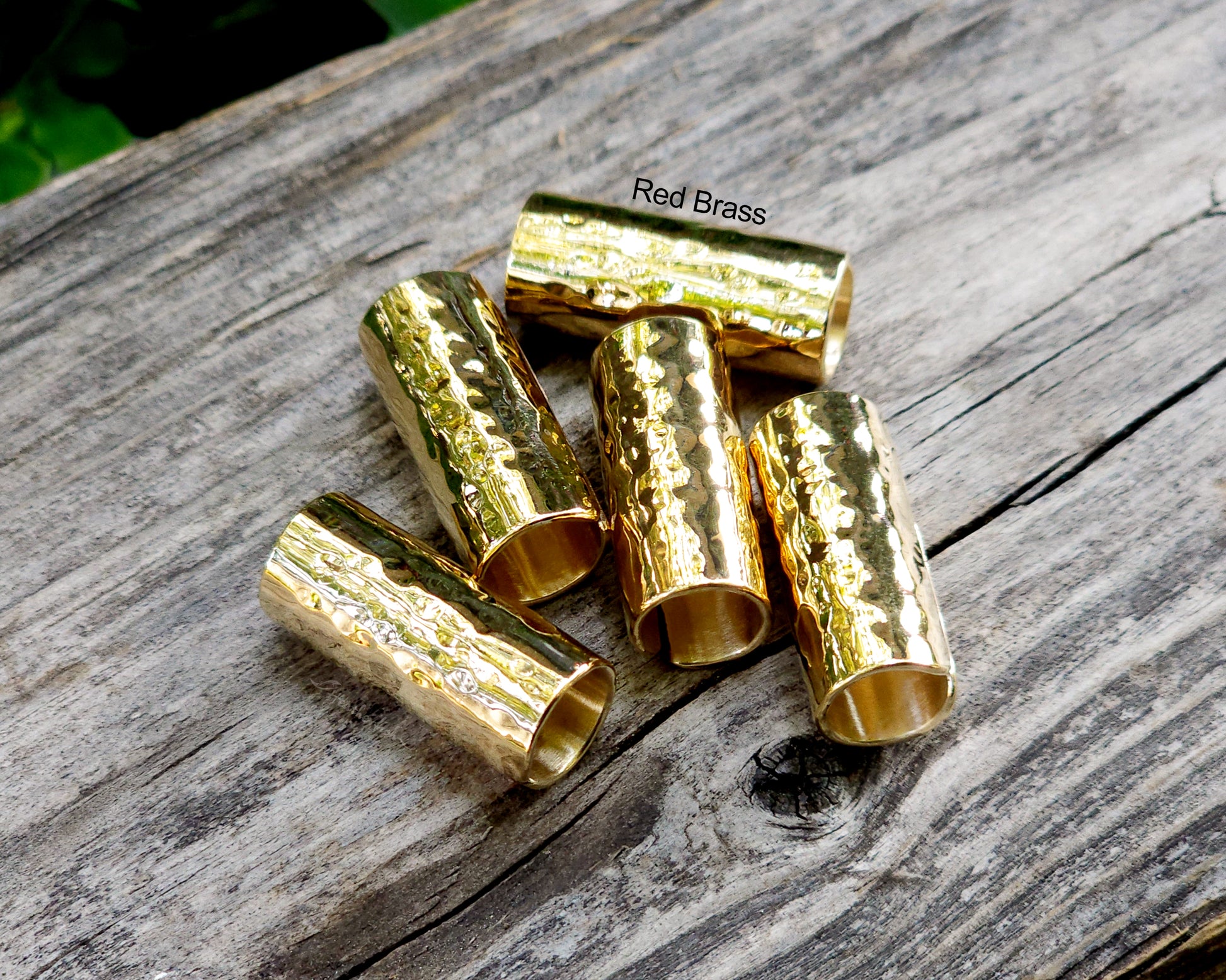 Red brass hair cuffs on a wood surface.