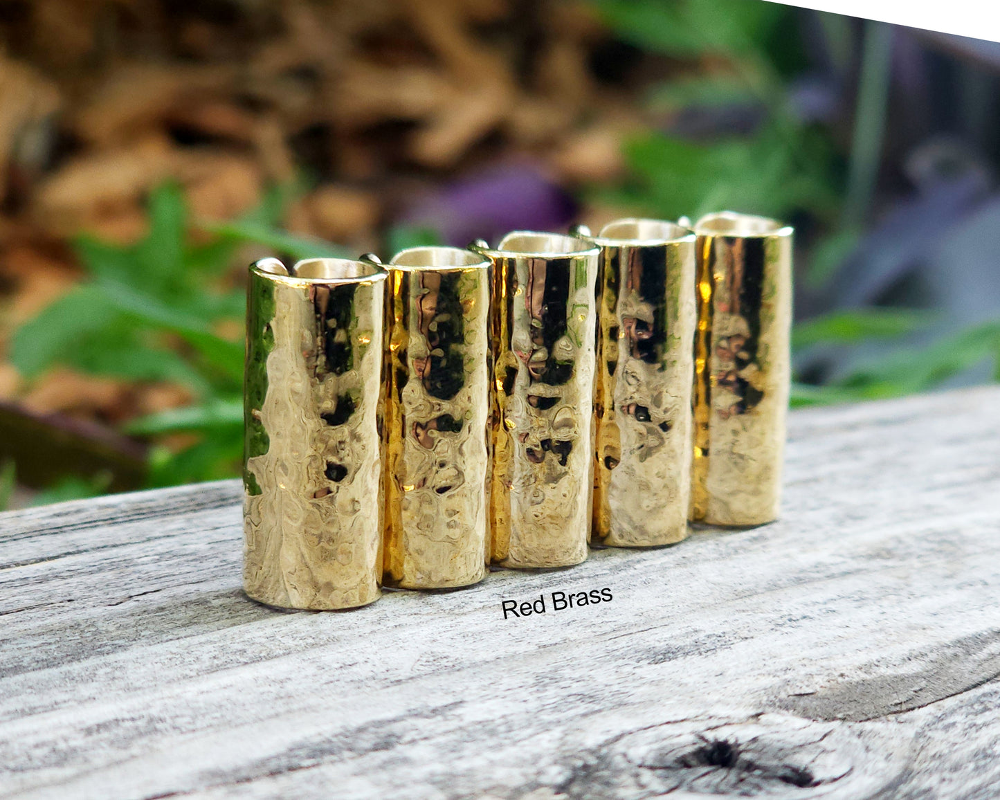 Red brass hair cuffs on a wood surface.