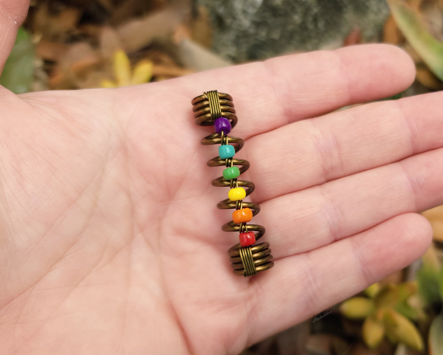 LGBTQIA+ pride loc bead held in hand to show scale.