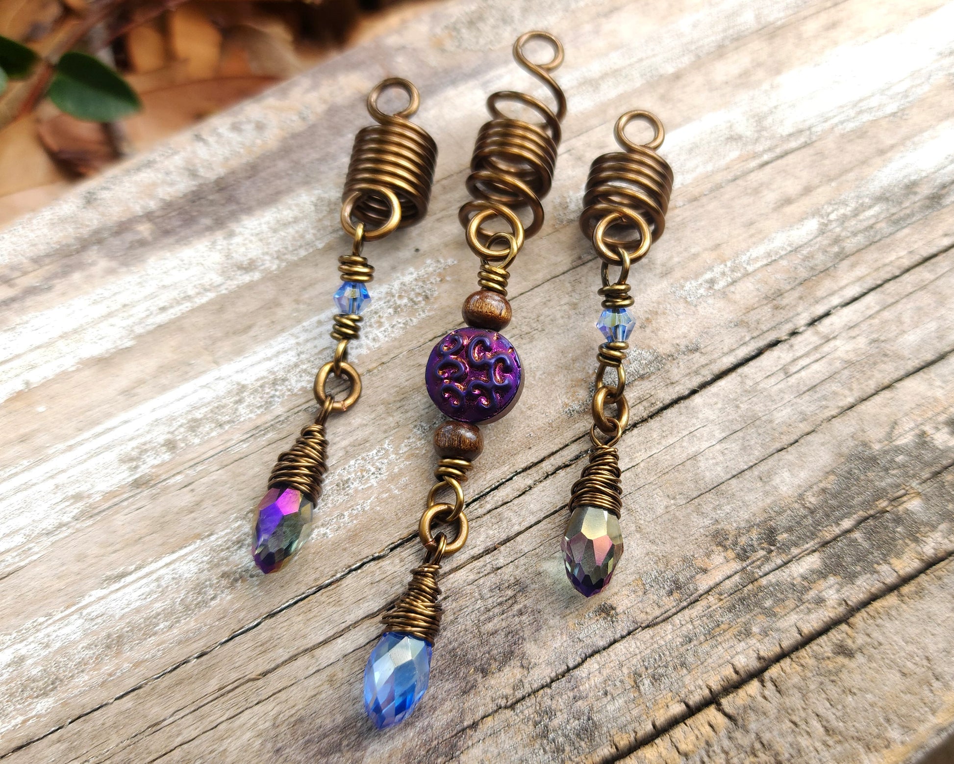 Set of 3 purple and periwinkle hair beads on a wood background.