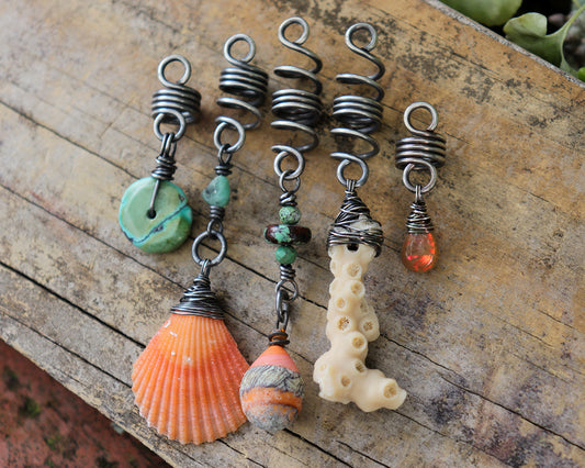 A set of five silver hair coils featuring an orange shell, white coral, orange artisan lampwork glass, Hubei Turquoise, aquamarine, and a Welo Ethiopian Opal.