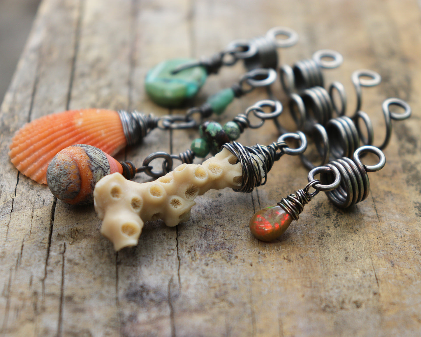 A set of five silver hair coils featuring an orange shell, white coral, orange artisan lampwork glass, Hubei Turquoise, aquamarine, and a Welo Ethiopian Opal.