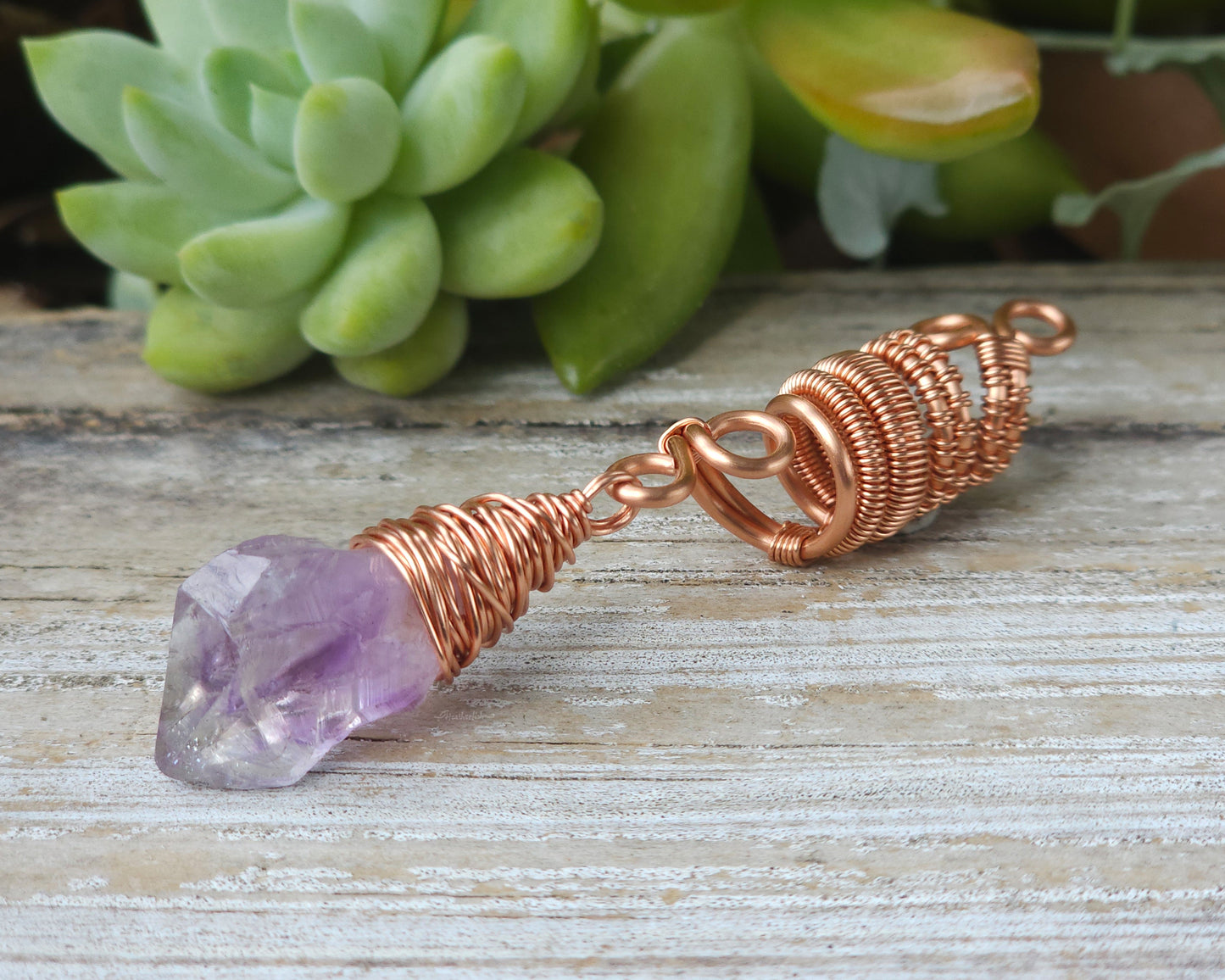 A woven copper dread bead featuring a raw Arkansas amethyst crystal point.