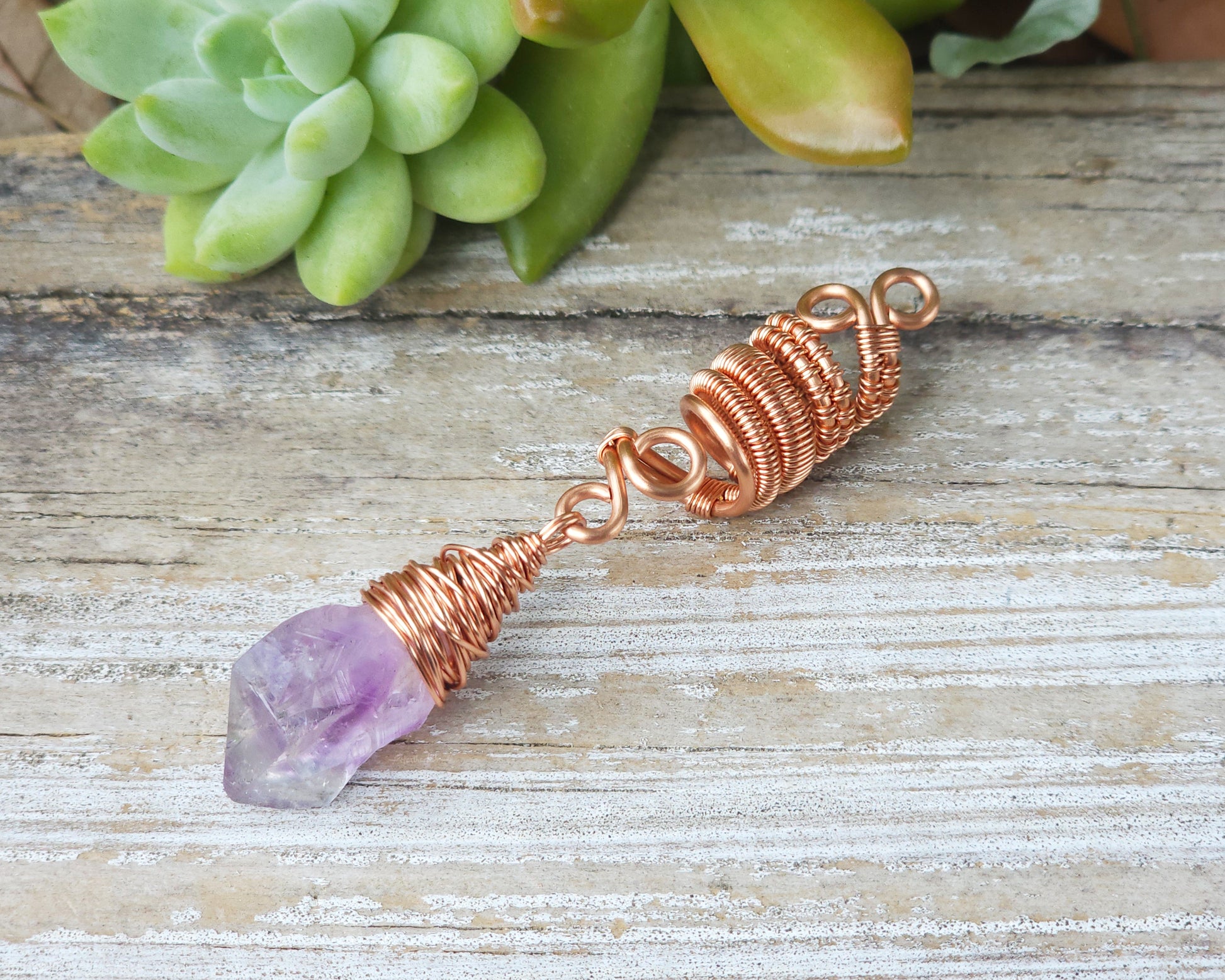 A woven copper dread bead featuring a raw Arkansas amethyst crystal point.