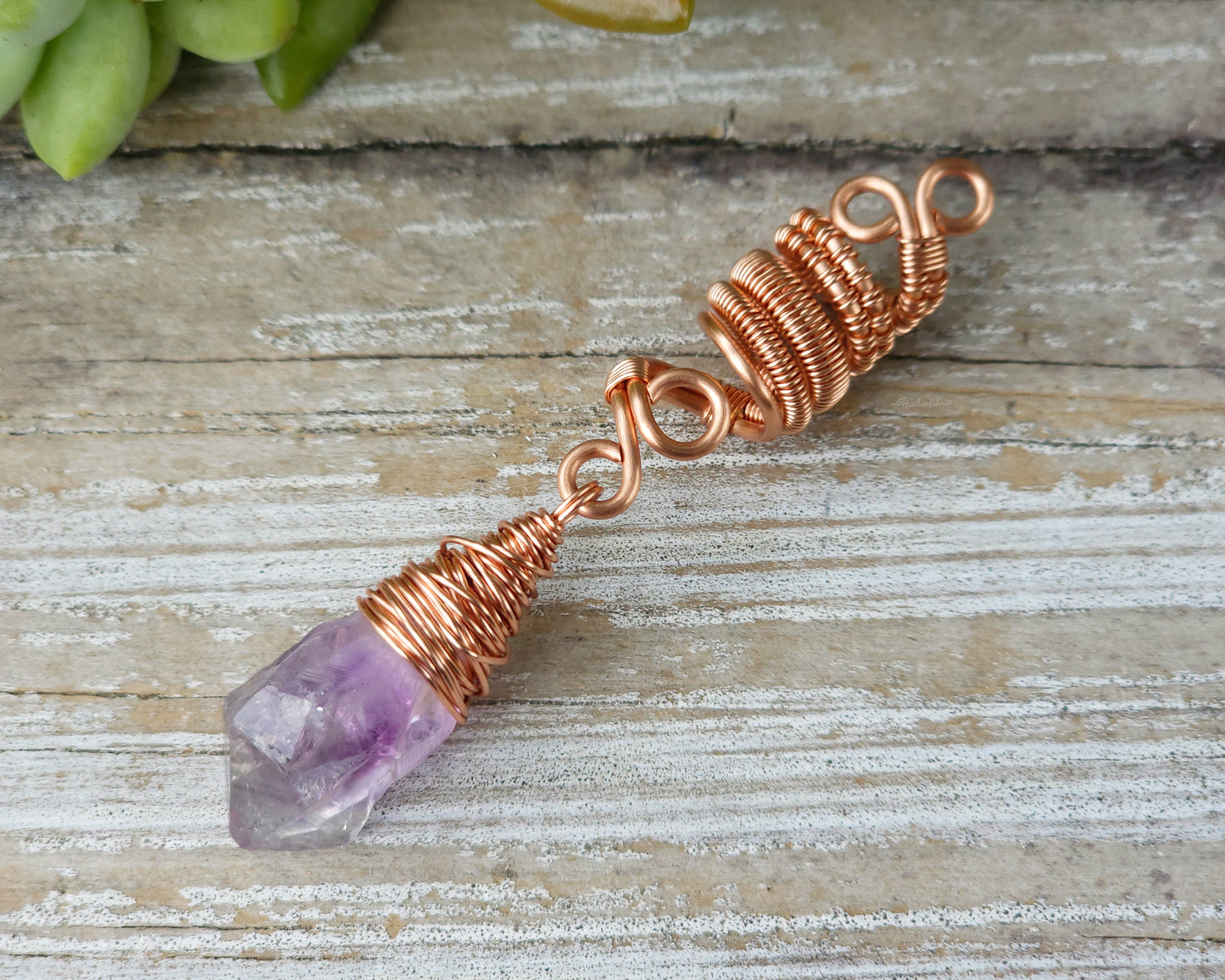 A woven copper dread bead featuring a raw Arkansas amethyst crystal point.