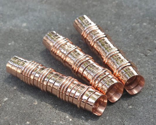 Three extra long copper hair coils on stone background.