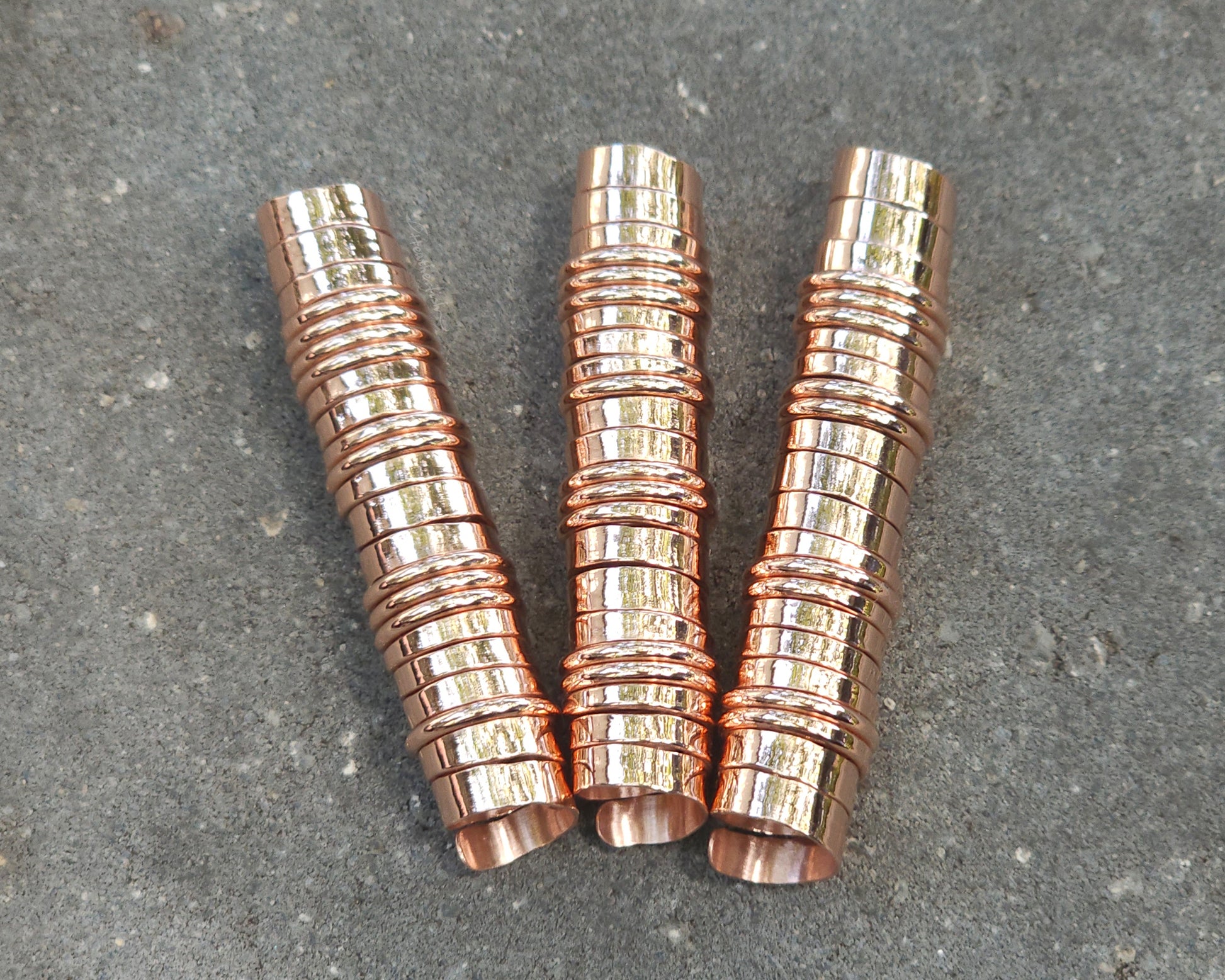Three extra long copper hair coils on stone background.