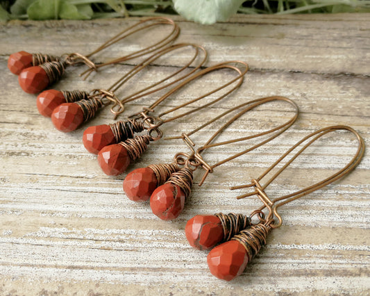 Grouping of pairs of red jasper earrings on a wood background.