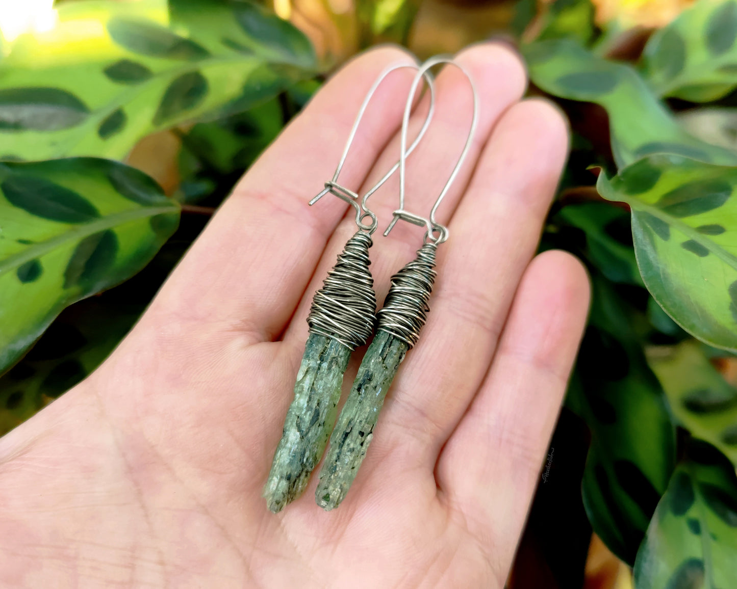 Silver green kyanite earrings held in hand to show scale.