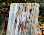 Orange kyanite earrings on a wood background.