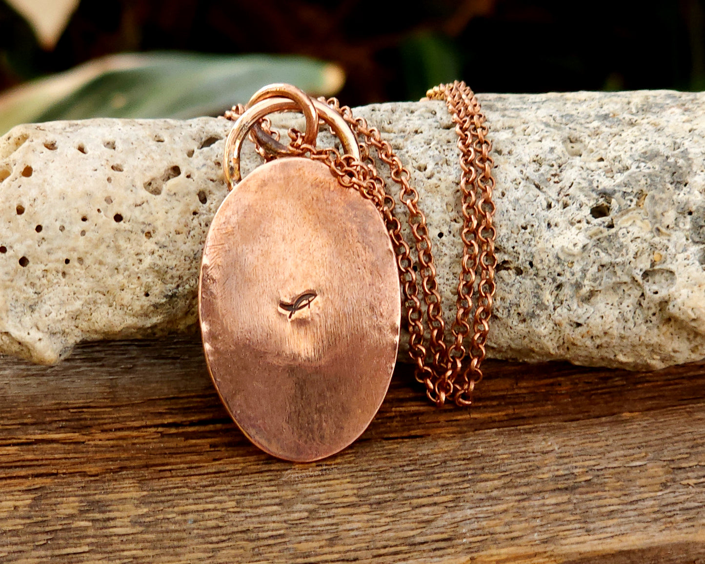 Backside of a copper and labradorite pendant on a wooden surface
