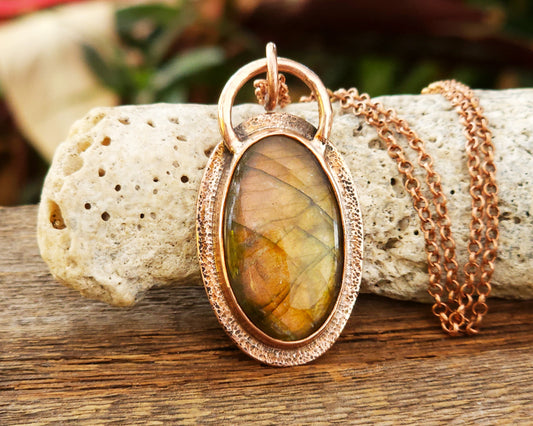 Copper and labradorite pendant on a wooden surface
