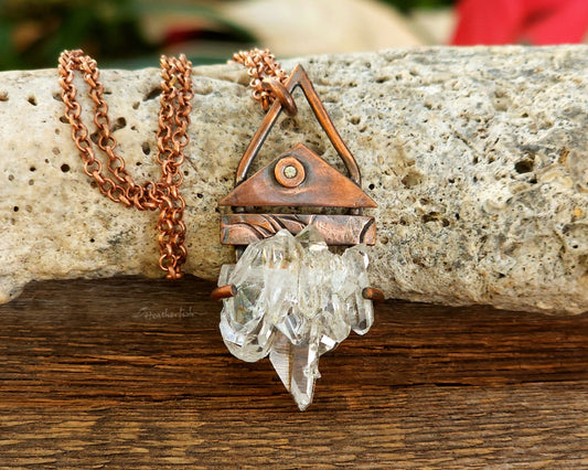 Copper necklace with a crystal pendant on a stone surface