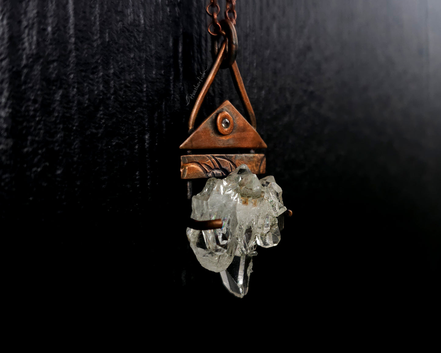 Necklace with a triangular pendant and crystal-like element on a dark background