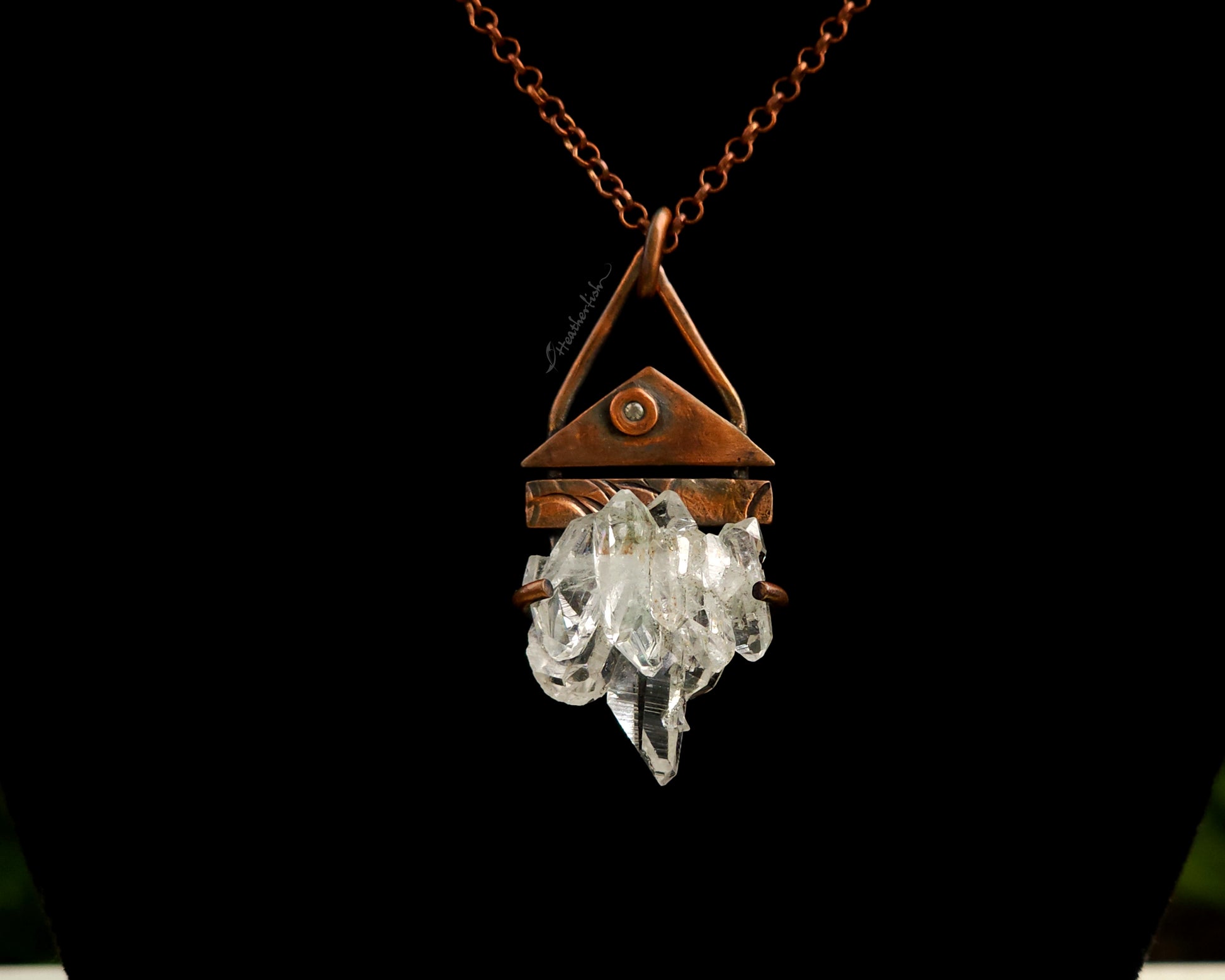 Necklace with a copper pendant featuring crystal elements on a black background