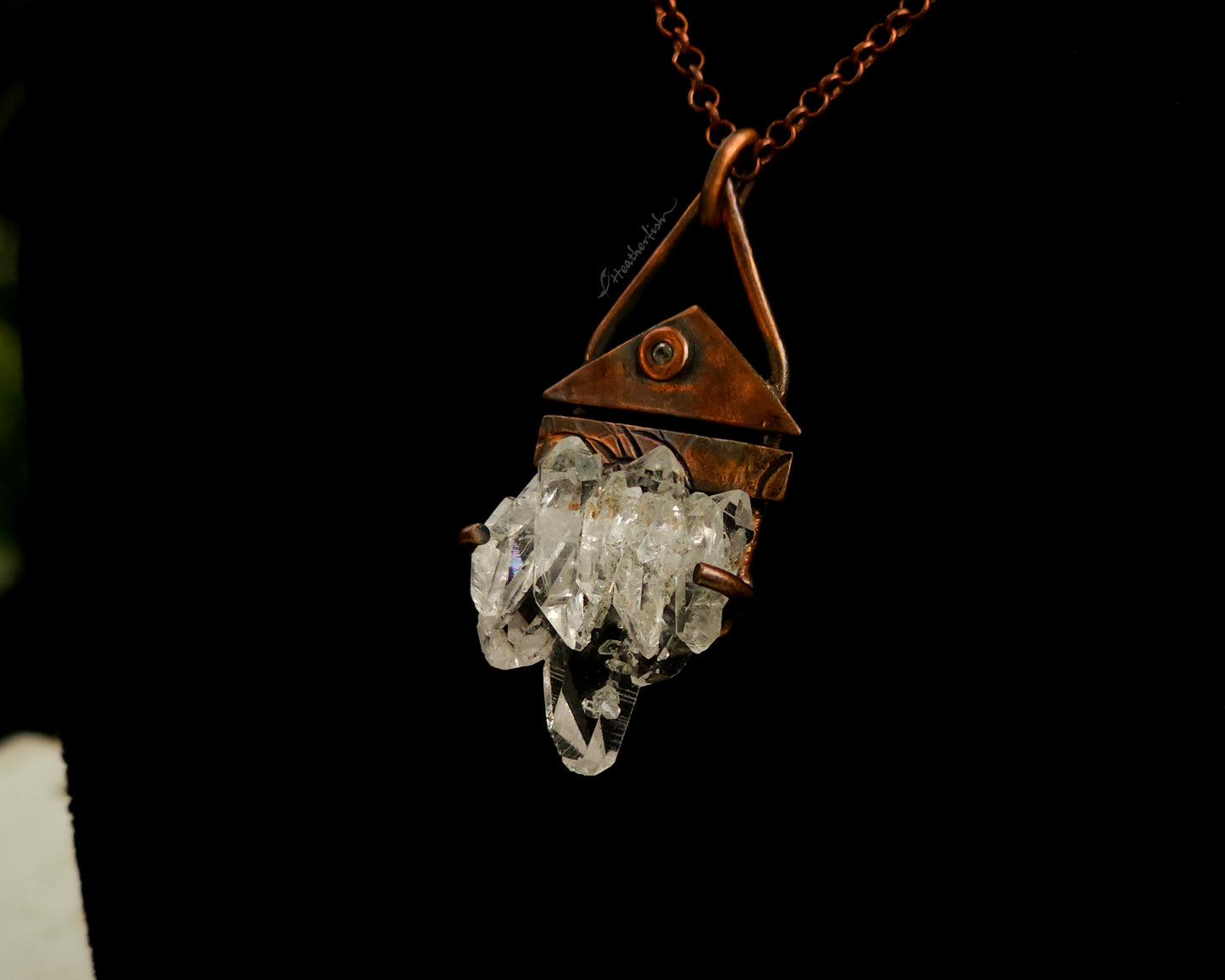 Crystal pendant necklace with copper chain on a dark background