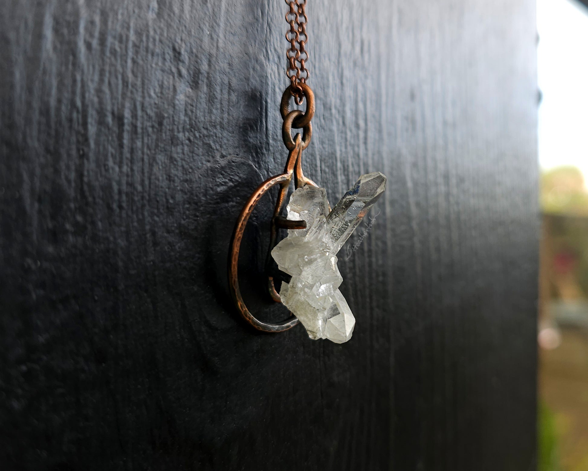 Crystal necklace with a copper chain on a dark textured background