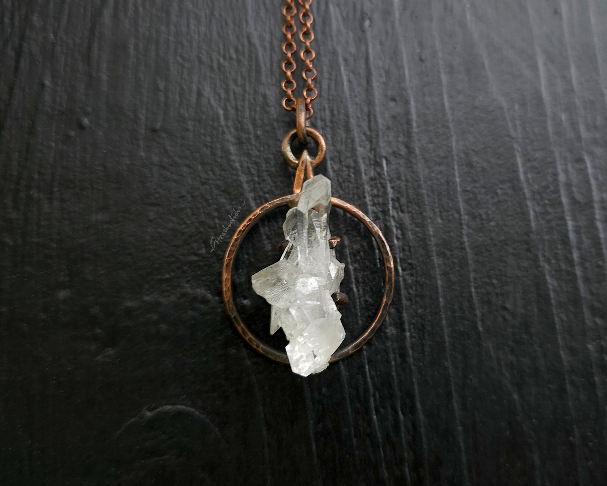 Necklace with a copper chain and crystal pendant on a dark surface