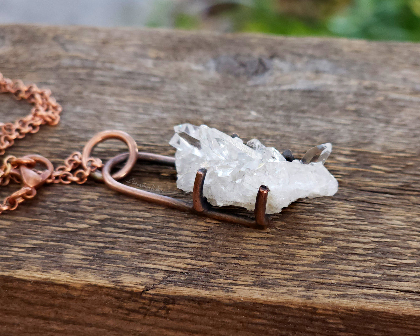 Quartz cluster necklace on a wood background.