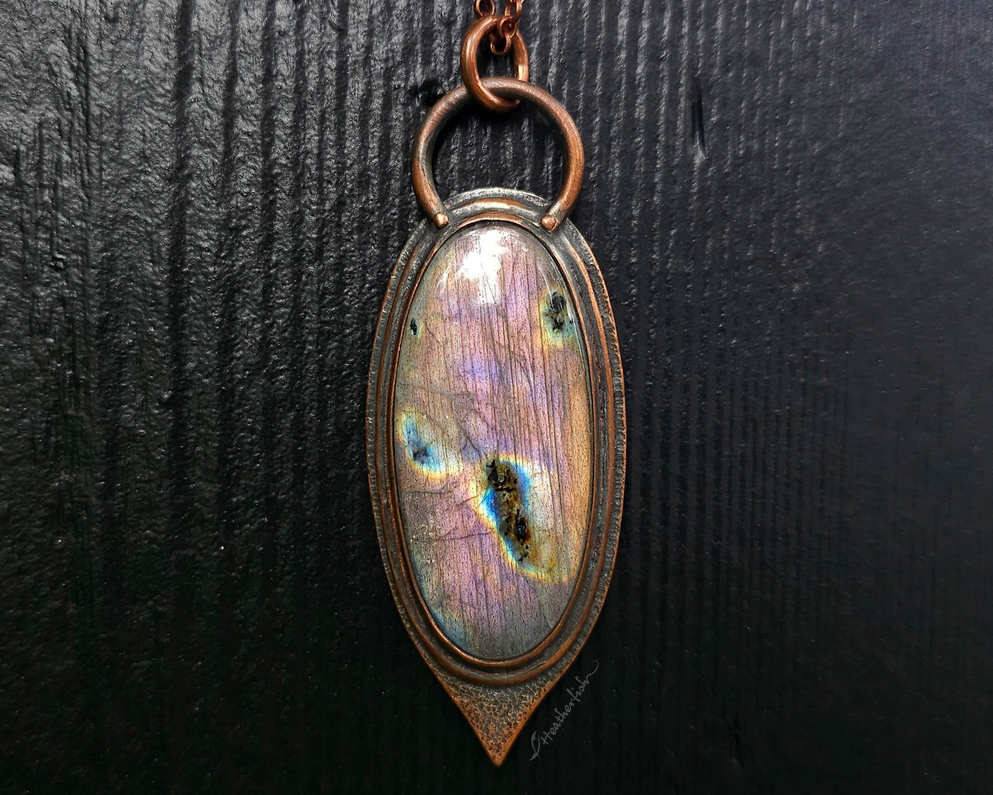 Necklace with an oval pendant featuring a colorful stone on a dark background