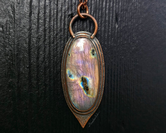 Necklace with an oval pendant featuring a colorful stone on a dark background