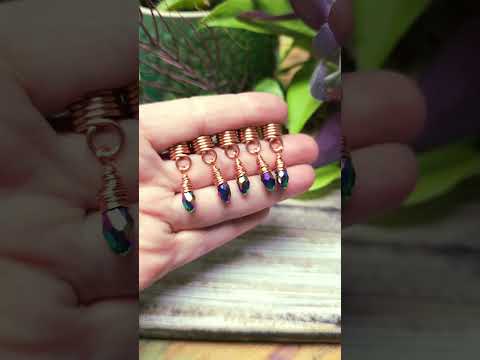 Set of five copper and rainbow hair beads held in hand with wood and plants in the background.