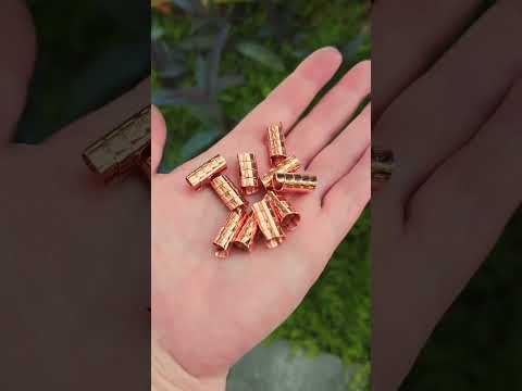 Set of 10 copper hair beads held in hand with plants in the background.