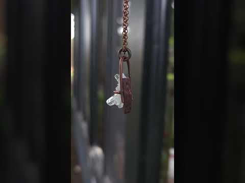 Mini quartz cluster necklace against natural background.