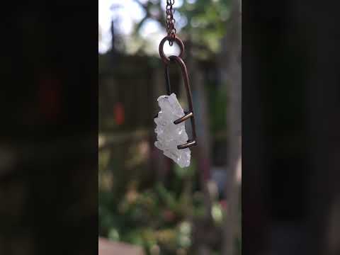 Quartz cluster necklace against a natural background.
