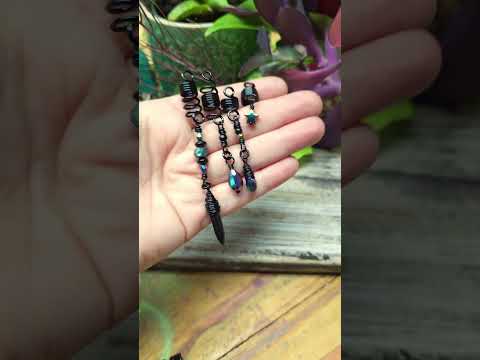 Set of 4 dread beads held in hand against wood background.