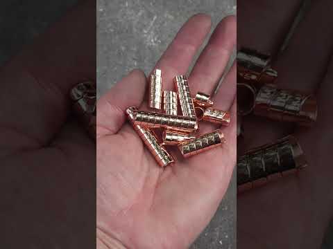 Set of 10 handmade copper hair coils held in a hand with a stone background.
