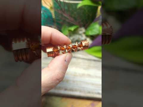 A garnet hair bead held in hand against a wood background.