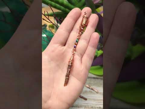 Hair bead held in hand with various plants in the background.