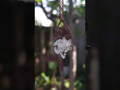 Crystal pendant suspended in front of a blurred natural background.