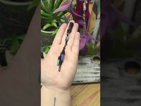 Hair Jewelry held in hand with plants and a wood board in the background.