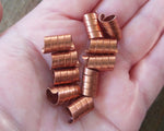 A set of 10 Copper Dread Beads in hand.
