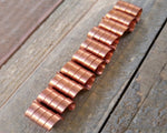 A line of Copper Dread Beads Set of 10 on a wooden background.