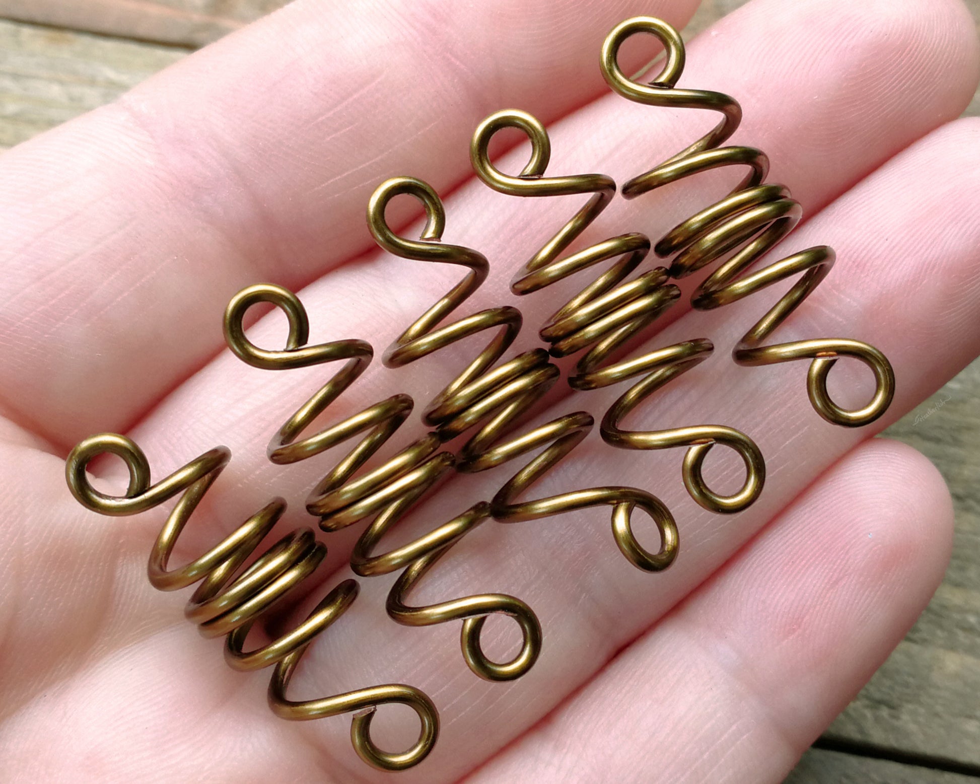 Set of 5 filigree beads on wood background displayed in hand to show scale.