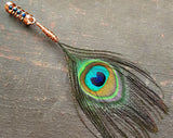 Peacock eye feather dread bead on a wood background.