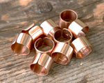 Set of 10 Copper Cuffs on a wood background.