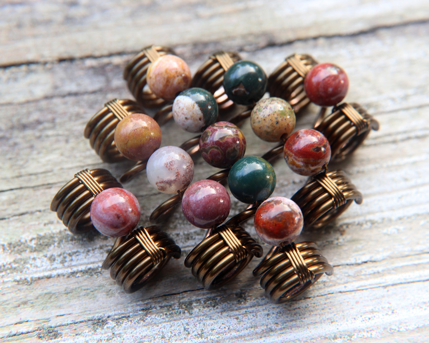 Set of 5 jasper dread beads on white washed wood background.