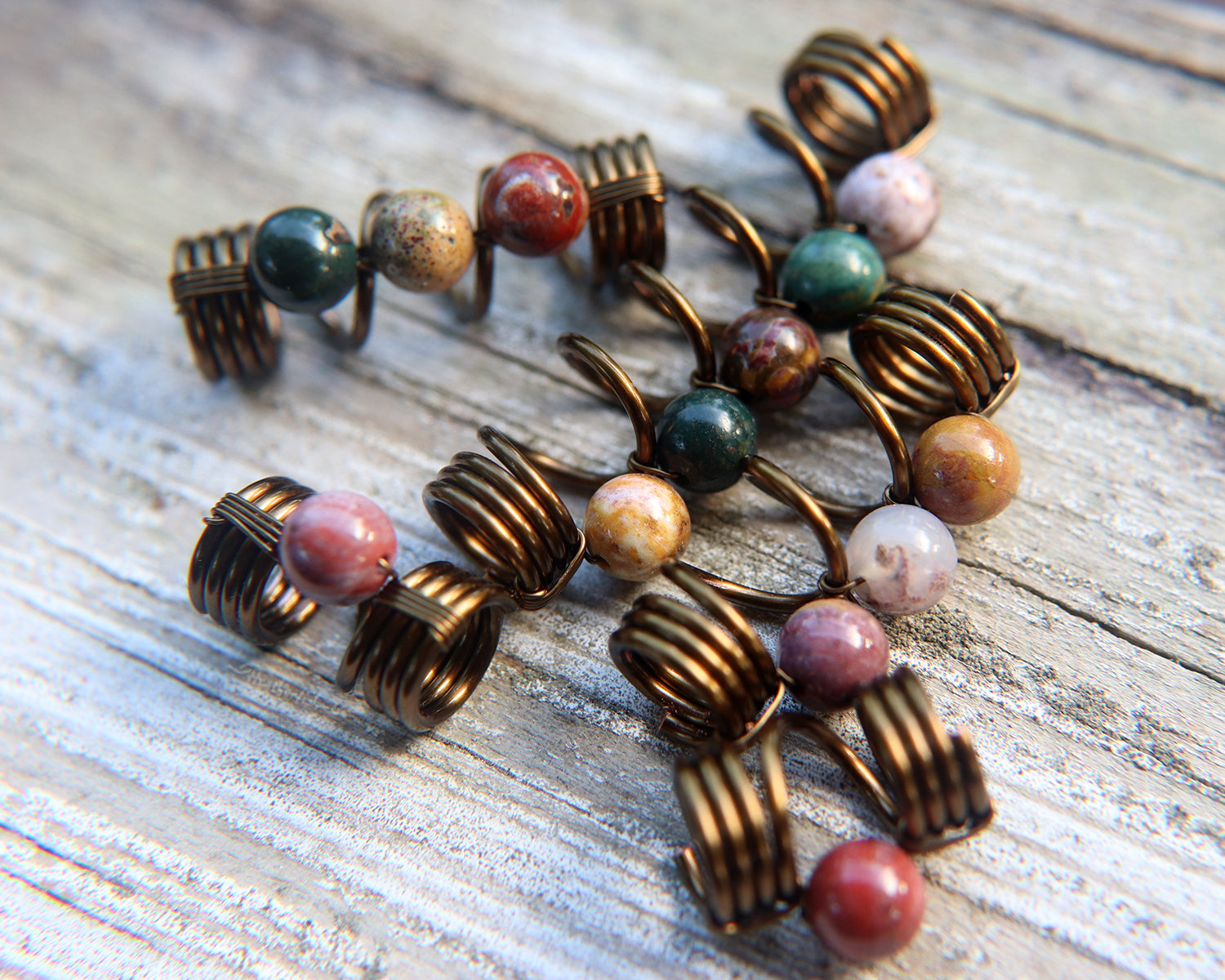 Set of 5 jasper dread beads on white washed wood background.
