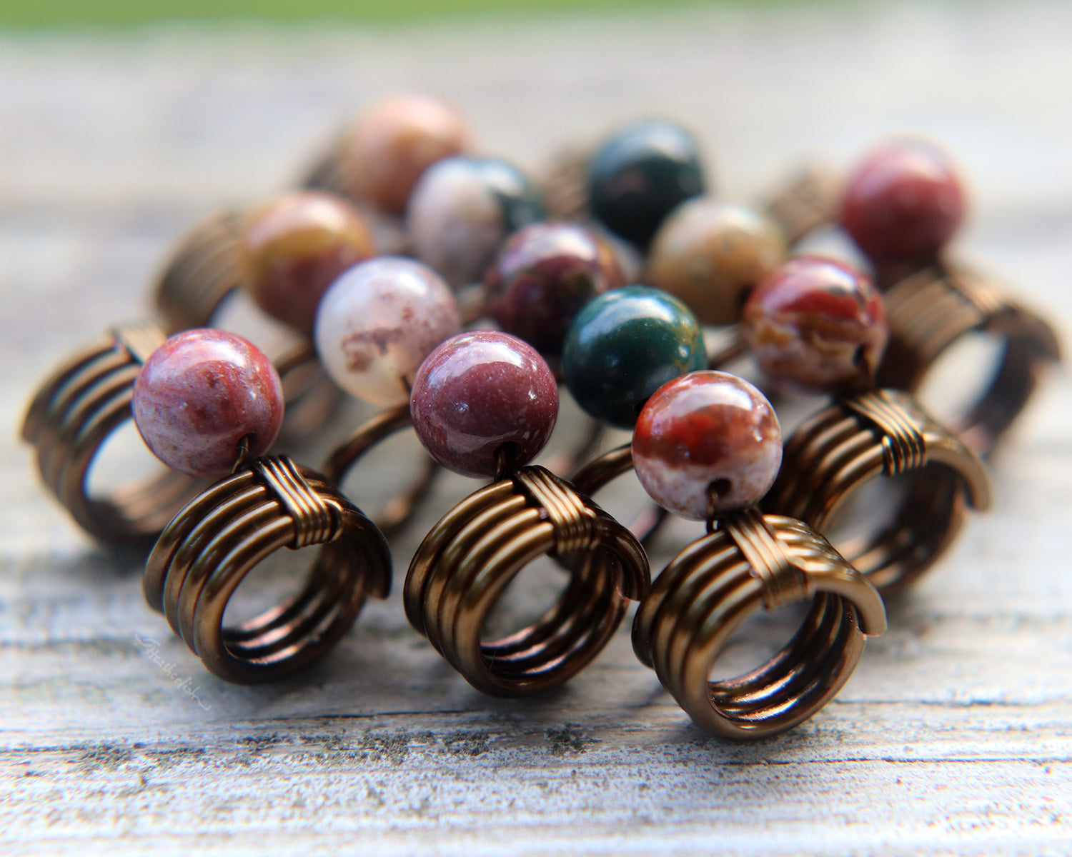 Set of 5 jasper dread beads on white washed wood background.